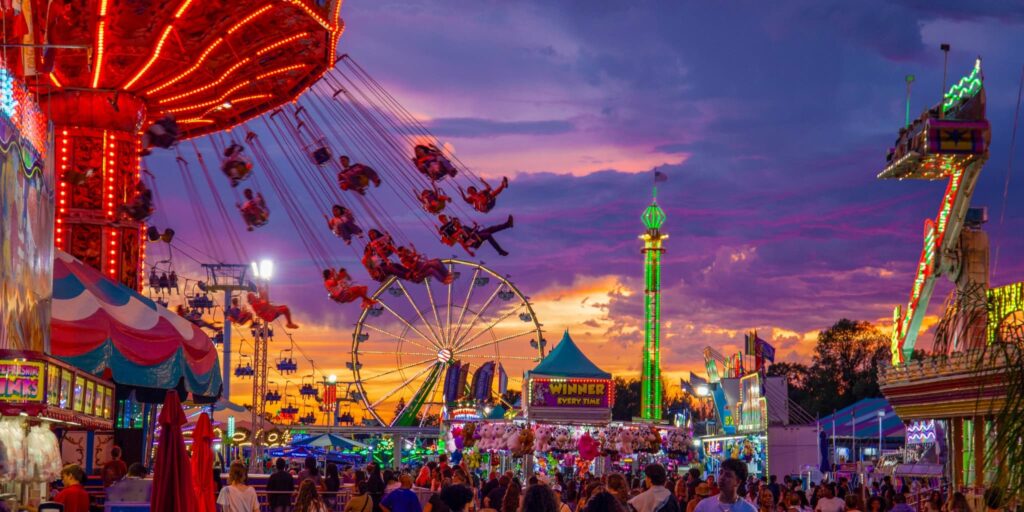 Fairgoers ride the Ferris wheel and other fun rides at sunset at the California State Fair.