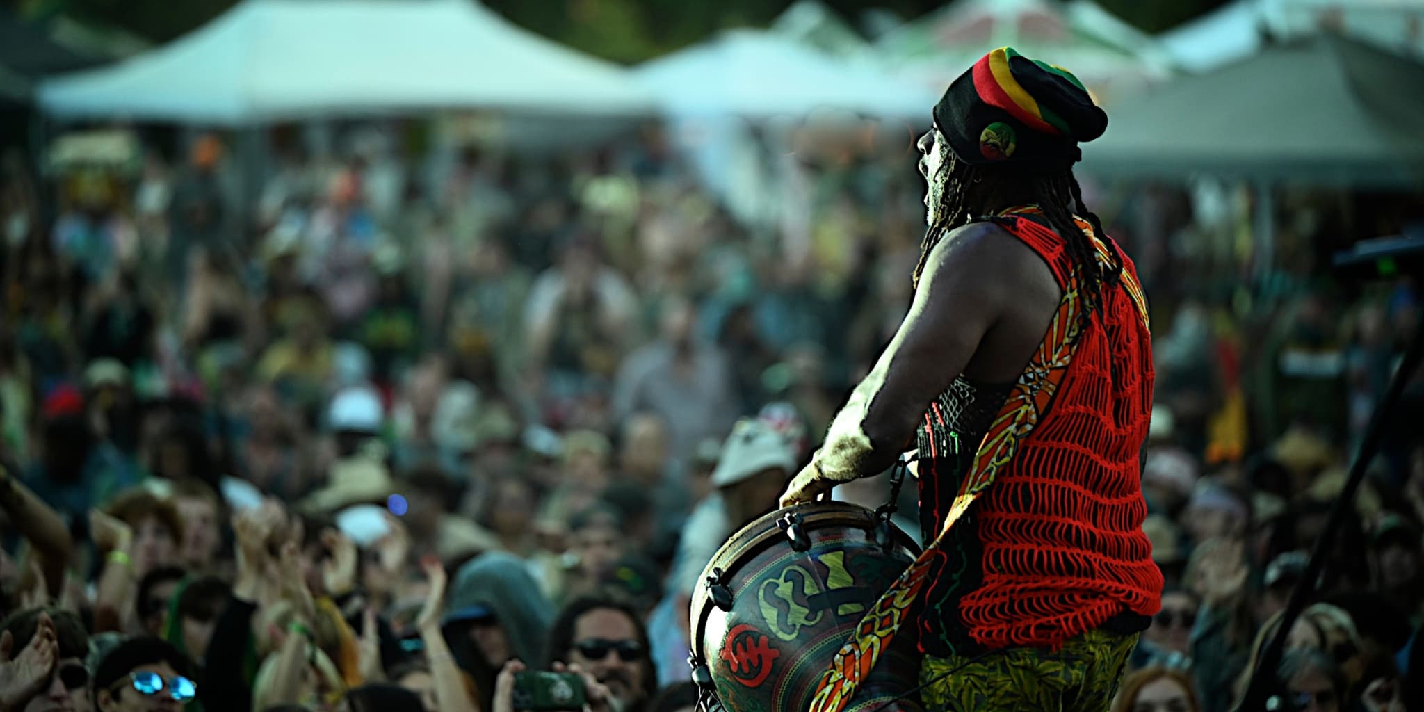 A reggae performer plays in front of a large crowd