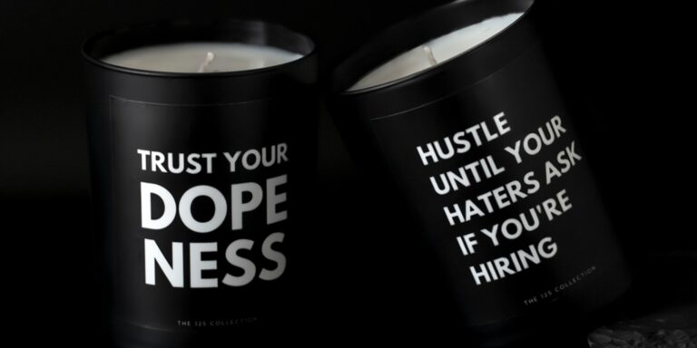 Candles from The 125 Collection that say "Trust Your Dopeness" and "Hustle Until Your Haters Ask If You're Hiring