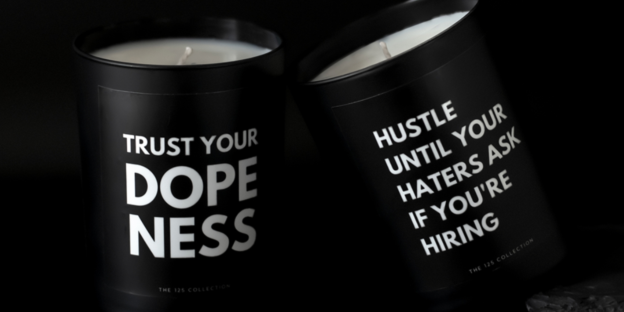 Candles from The 125 Collection that say "Trust Your Dopeness" and "Hustle Until Your Haters Ask If You're Hiring