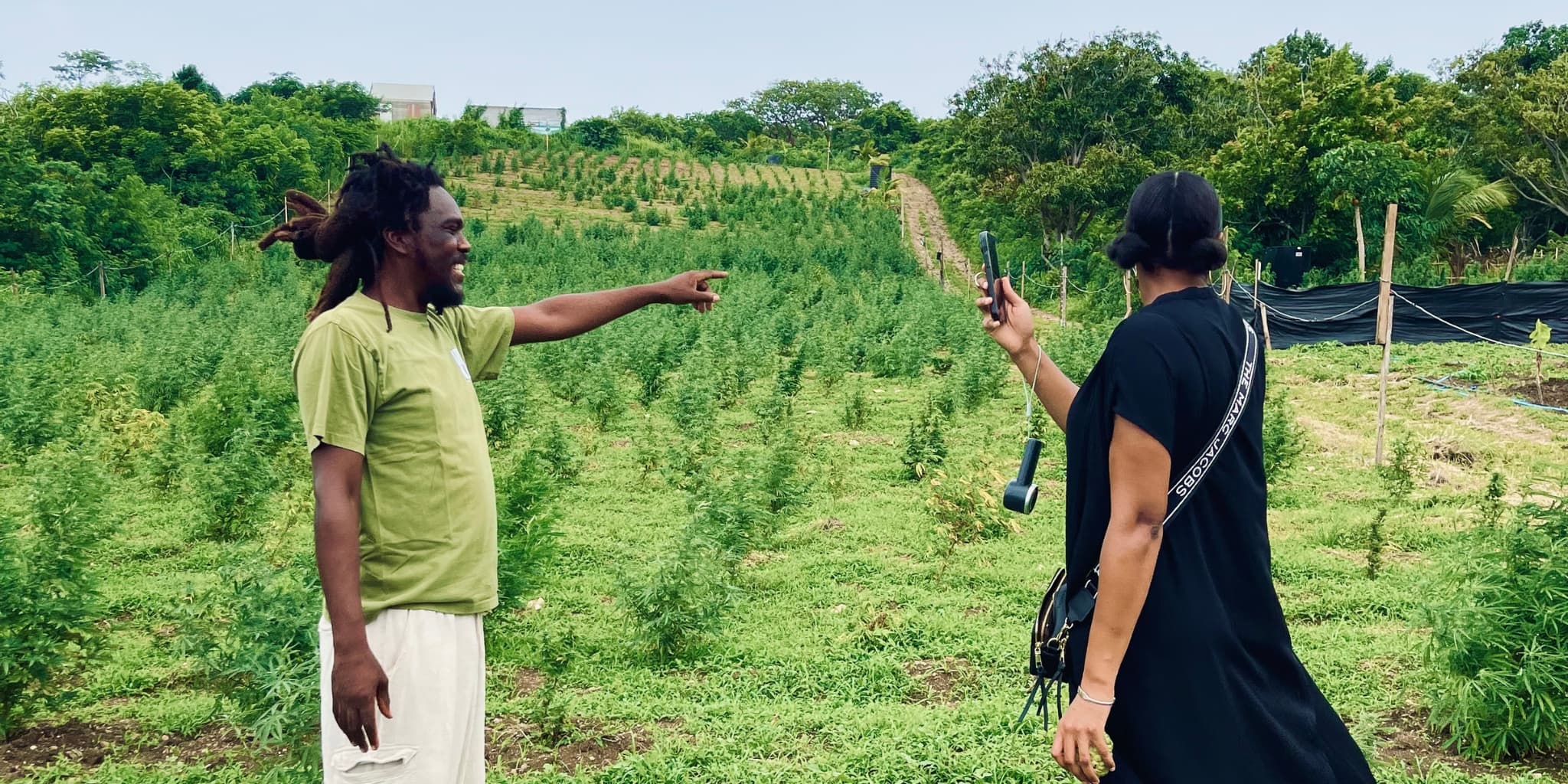Two people in front of a verdant farm