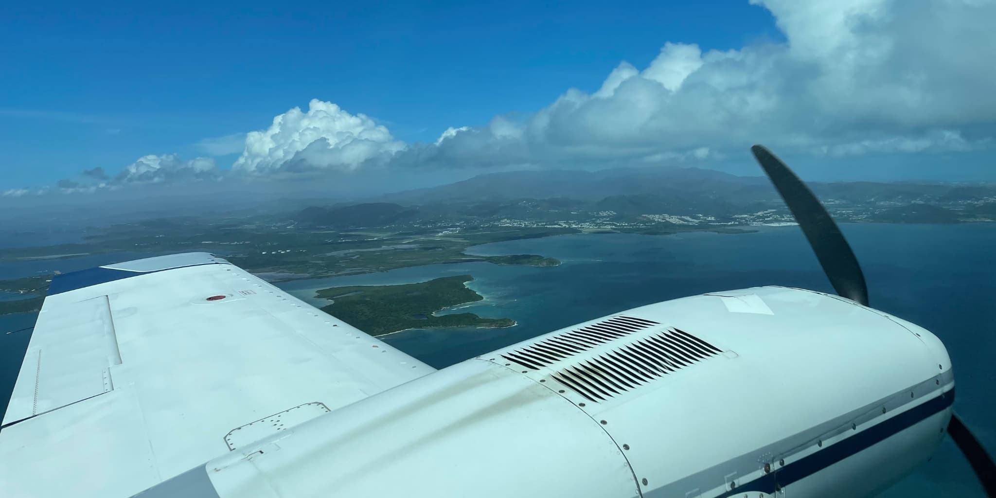 View out the window of a prop plane flying over the Caribbean Sea