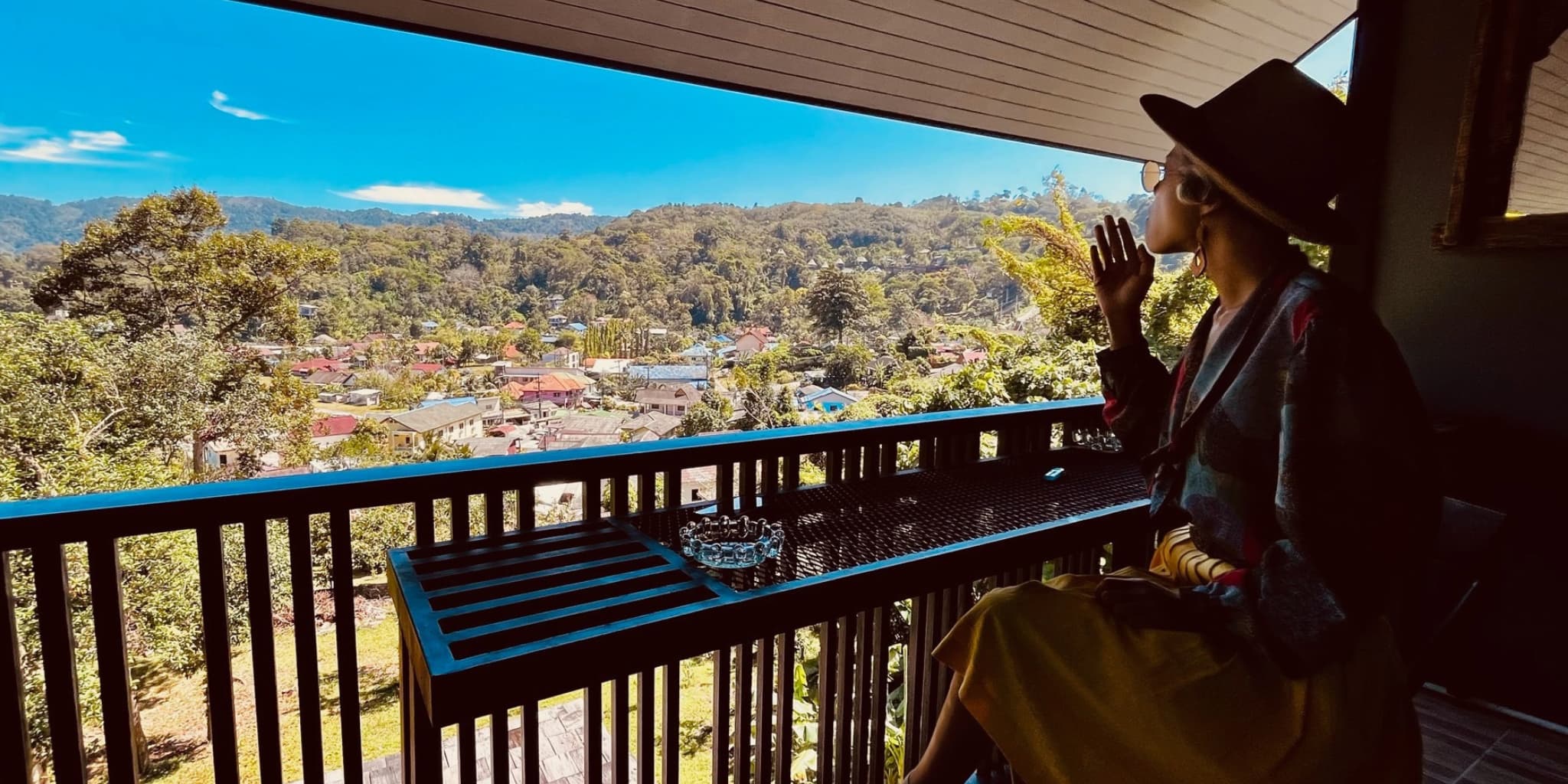 A woman smoking on a balcony overlooking the mountains