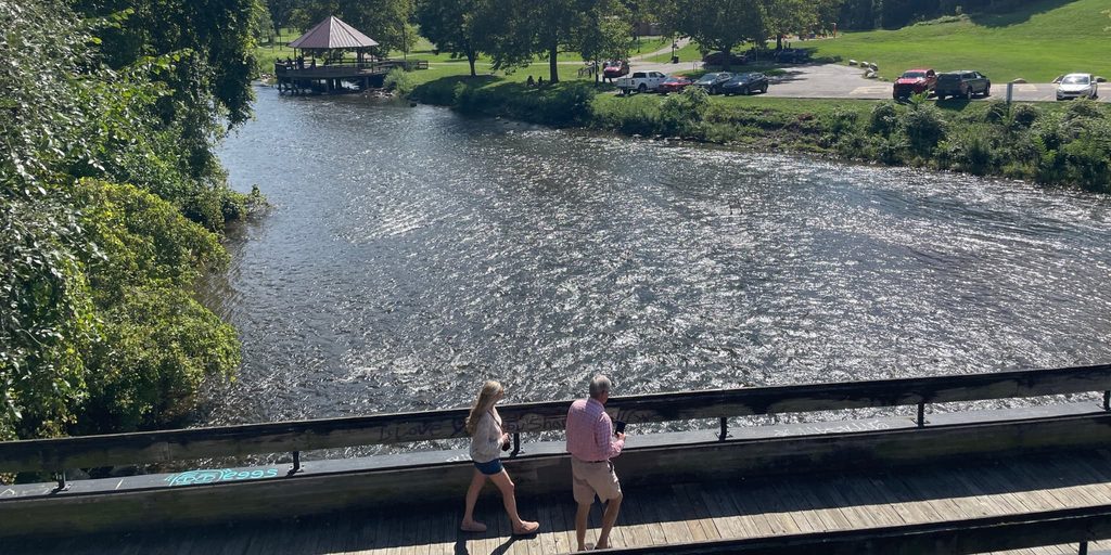 Two people on a bridge over a river